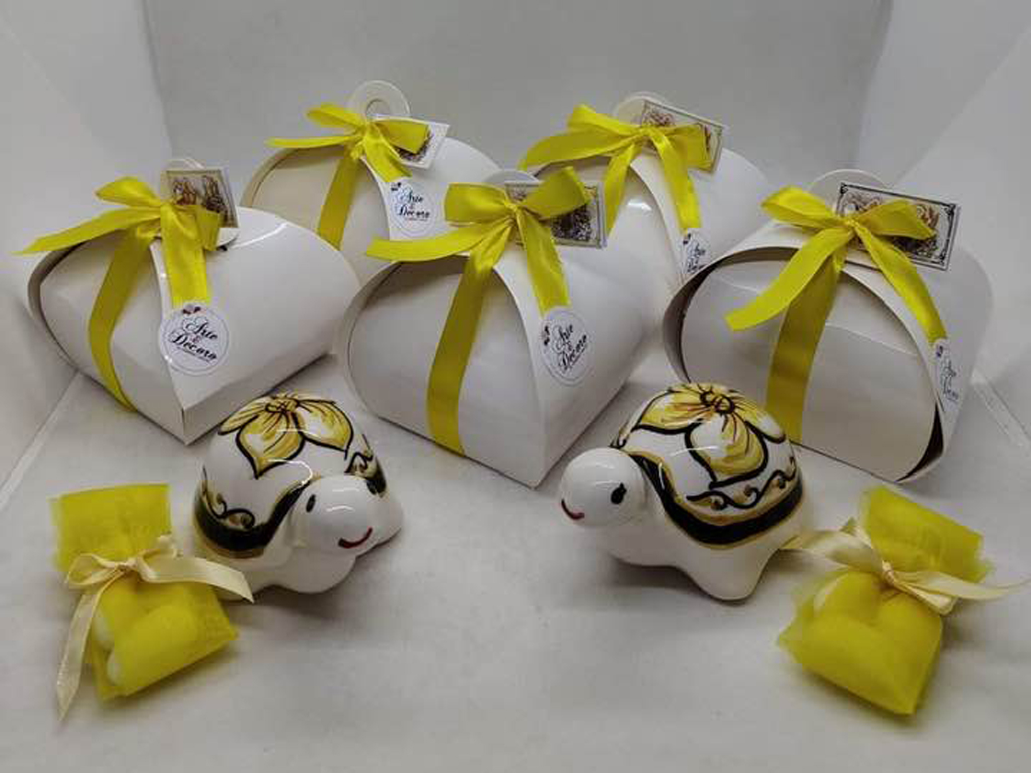 Assortimento di bomboniere a forma di lumachine portafortuna in ceramica siciliana, con gusci colorati in blu, arancio e giallo solare. Artigianato di Bronte firmato Arte&Decoro.