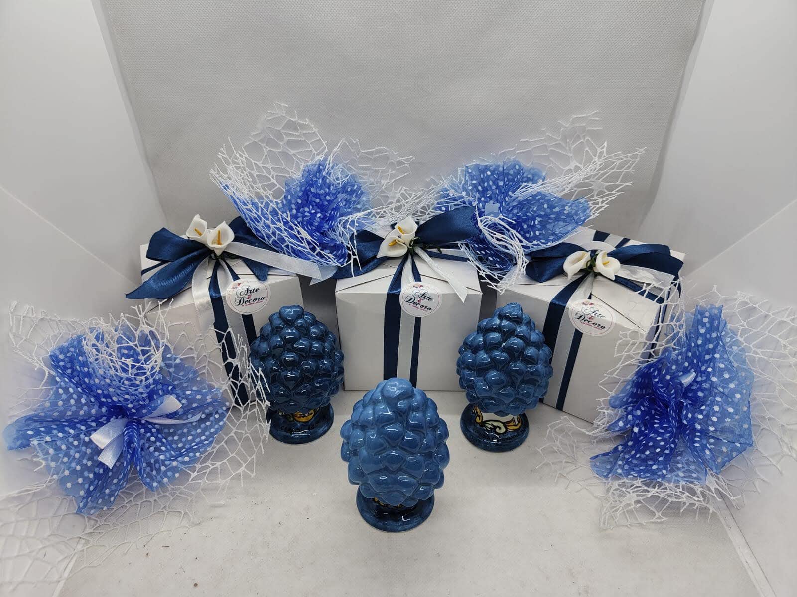Assortimento di bomboniere pigne siciliane in ceramica artigianale colorata nei toni del blu, giallo e arancio. Piccole pigne di buon auspicio realizzate a mano a Bronte da Arte&Decoro.