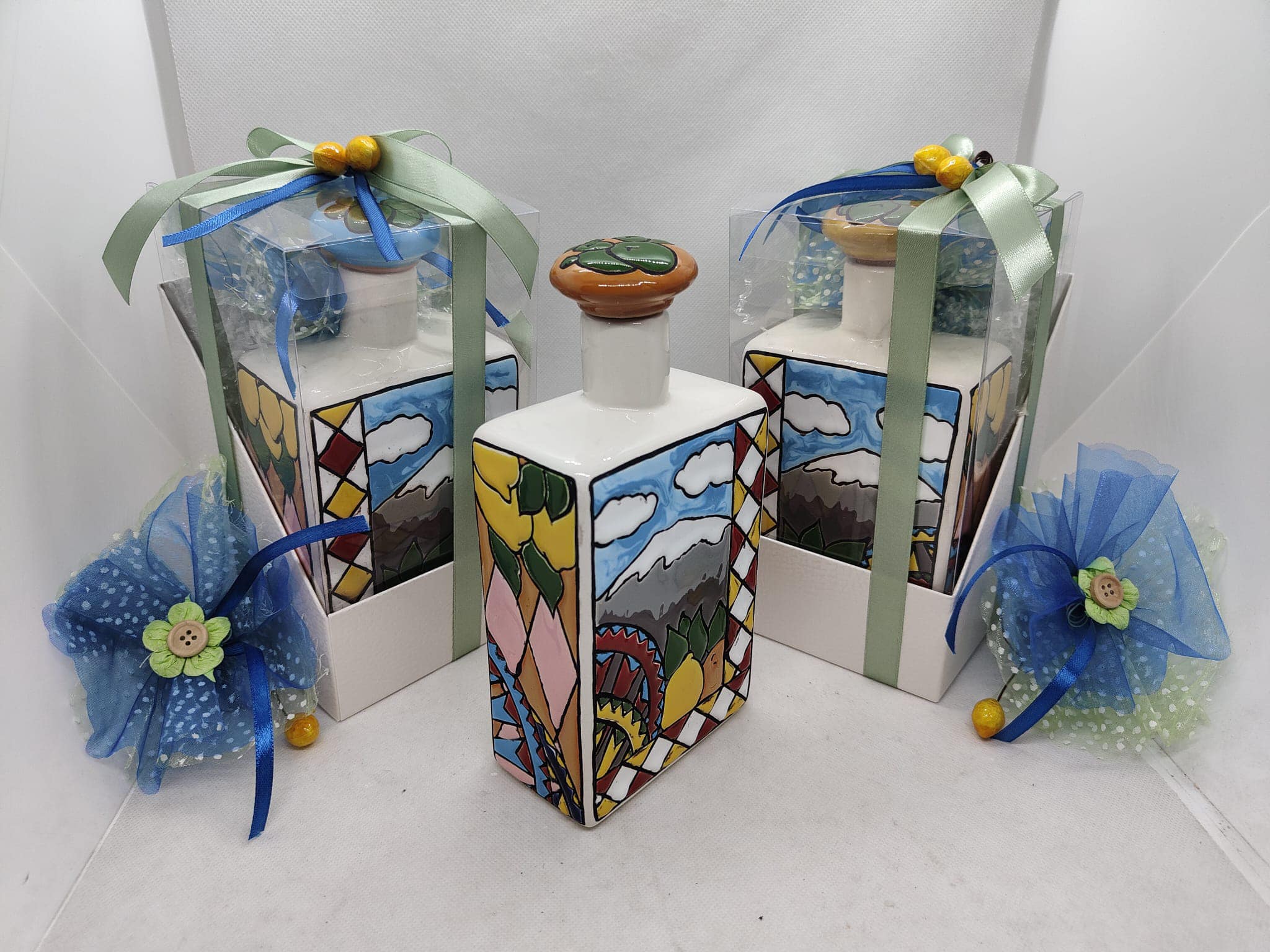 Piccole bottiglie oliere in ceramica maiolica decorate a mano con limoni, arance e motivi geometrici blu. Bomboniere utili siciliane realizzate a Bronte da Arte&Decoro.