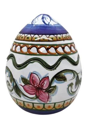 Uovo-scatola in ceramica maiolica lucida con decori tradizionali siciliani nei toni del verde pistacchio, oro caldo e fiori rosa vivace, foglie stilizzate e fiori gialli. Interamente fatto a mano a Bronte da Arte&Decoro, adatto come centrotavola pasqua
